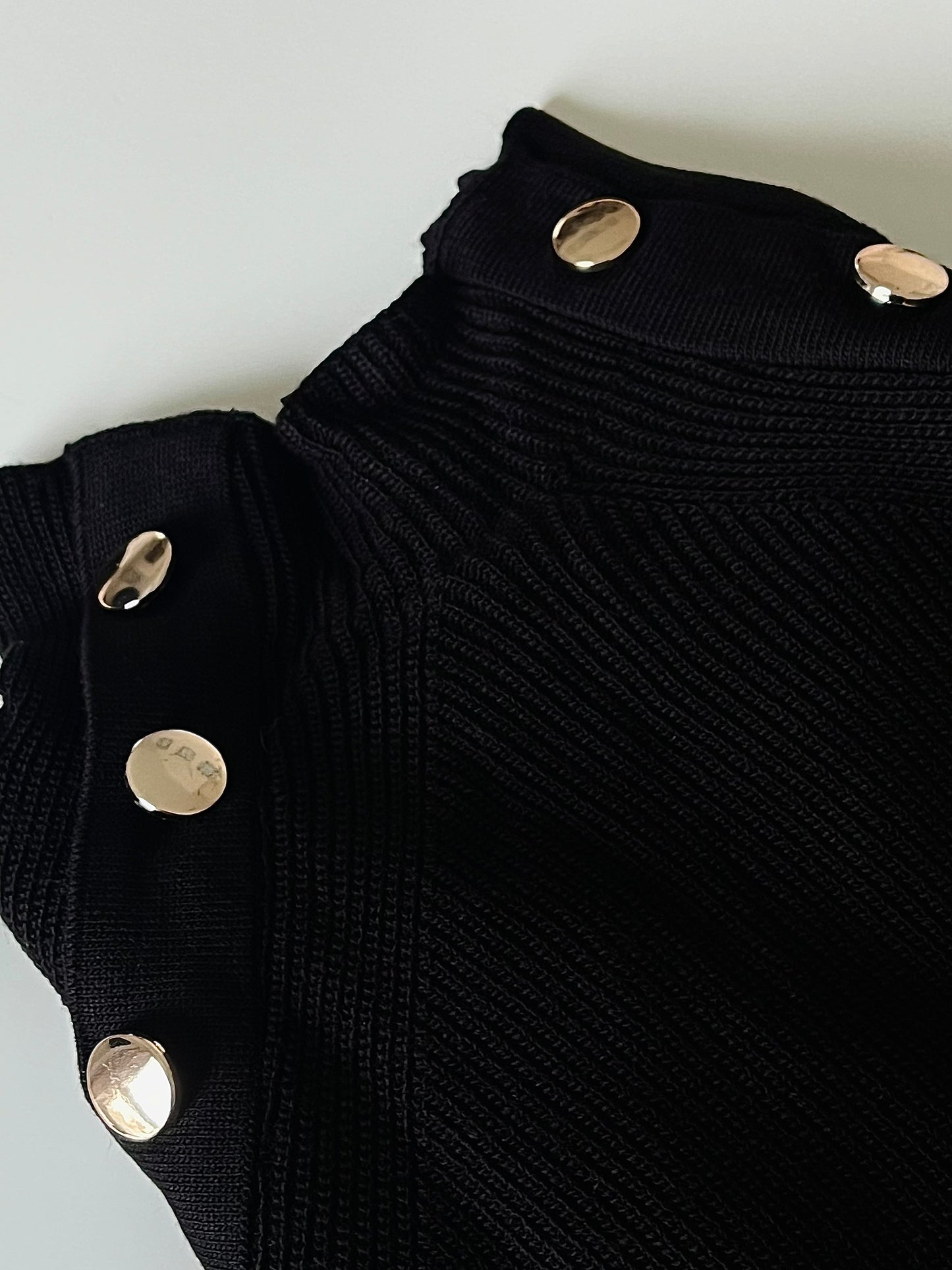 Schwarzer Pullover mit goldenem Knopf